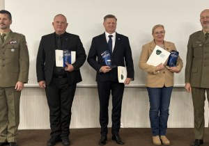 Troje przedstawicieli nagrodzonych szkół ze statuetkami i dyplomami pozuje z dwoma wojskowymi podczas forum w Lublinie.
