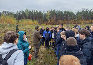 uczniowie słuchający wyjaśnień leśniczego na temat czekającego ich zadania